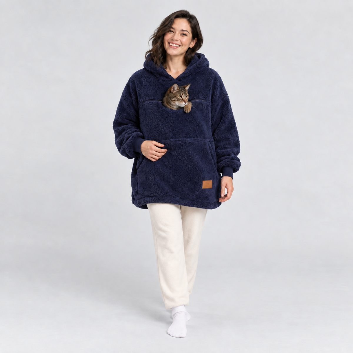 Woman wearing the navy sherpa pet carrier hoodie with a tabby cat in the front pouch.